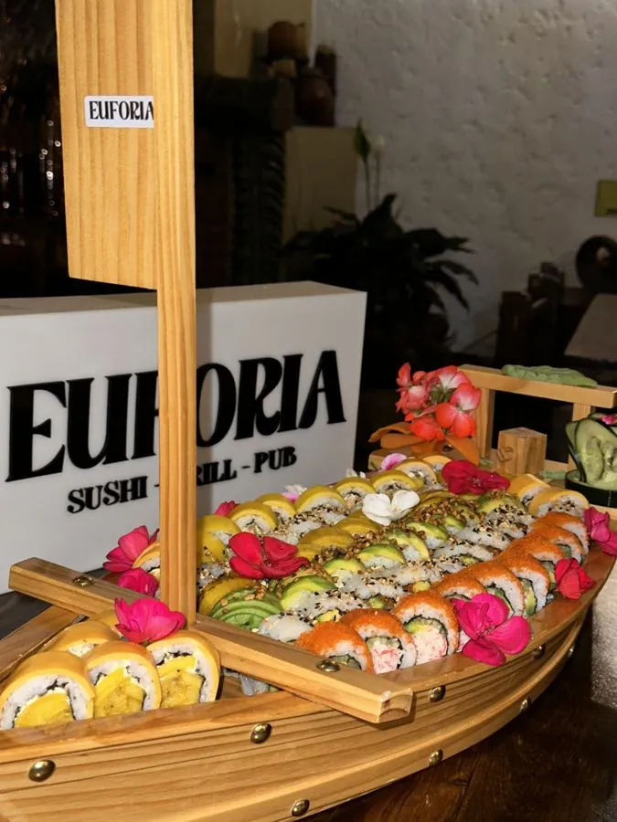 Barco de sushi decorado con flores frente al letrero de EUFORIA