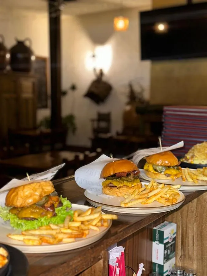 Hamburguesas con papas recién servidas sobre la barra, con el salón al fondo
